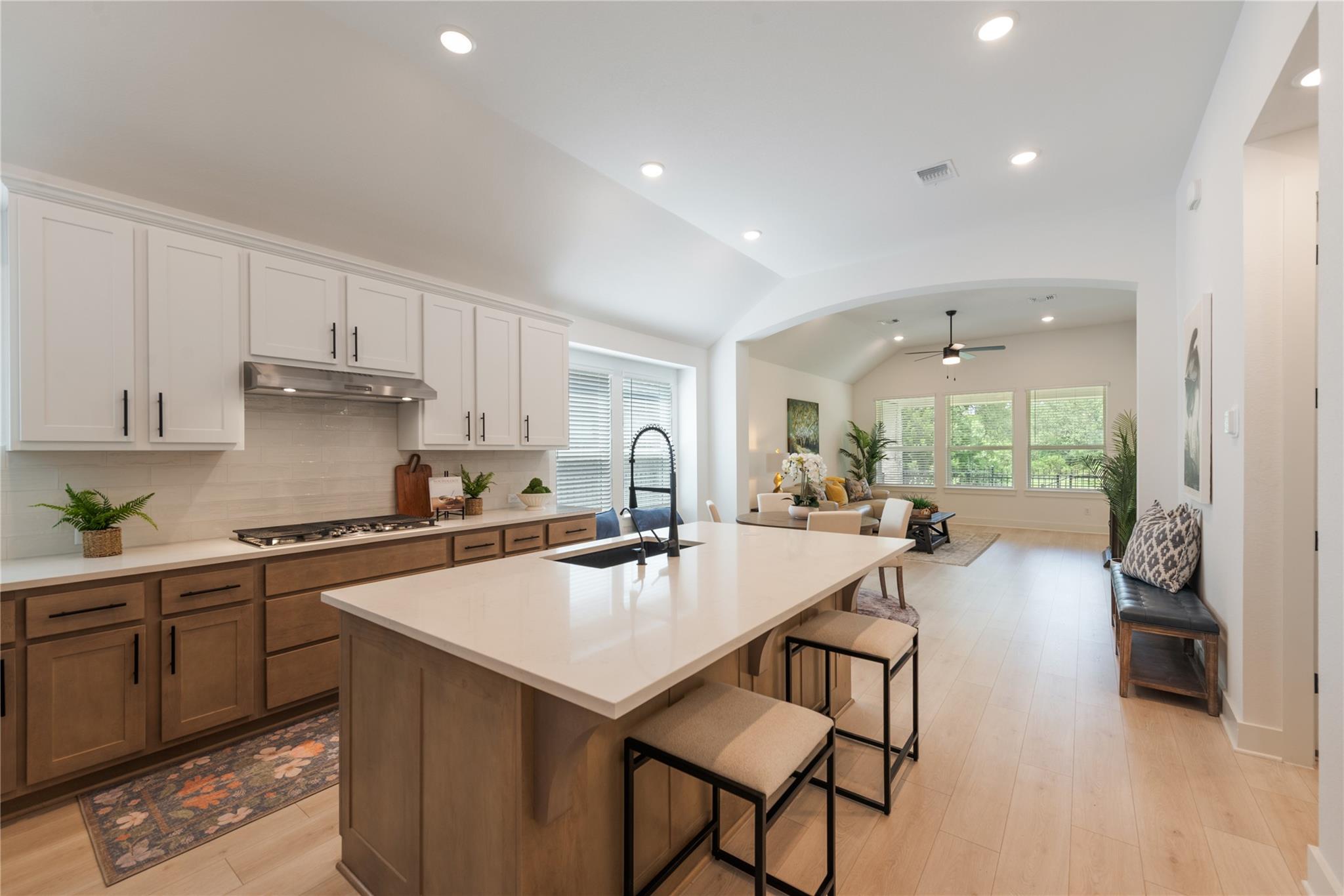 Open kitchen with a large island, white cabinets, and an adjoining furnished living room.