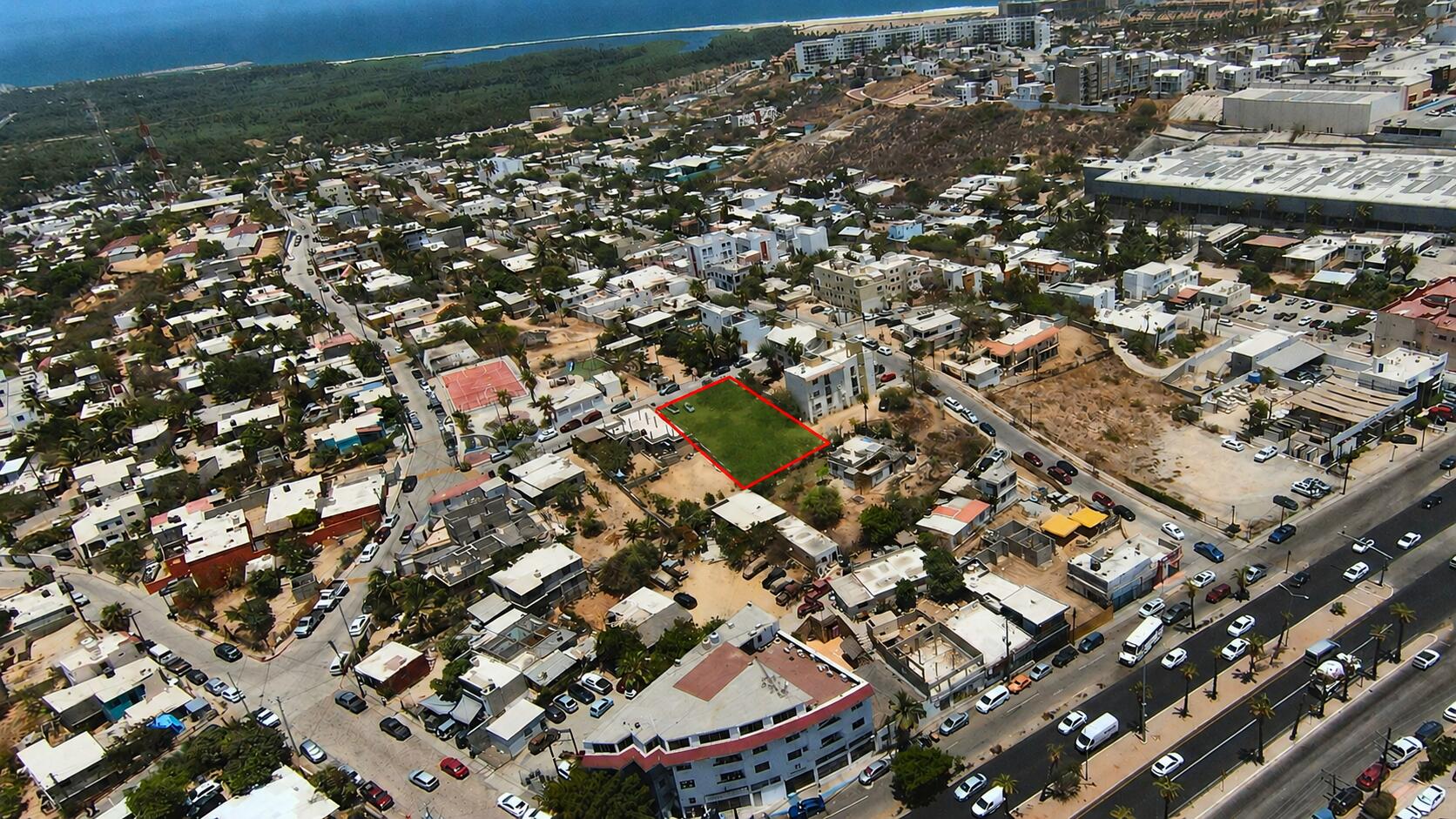 Aerial view of a vacant lot outlined in red amid a dense neighborhood.