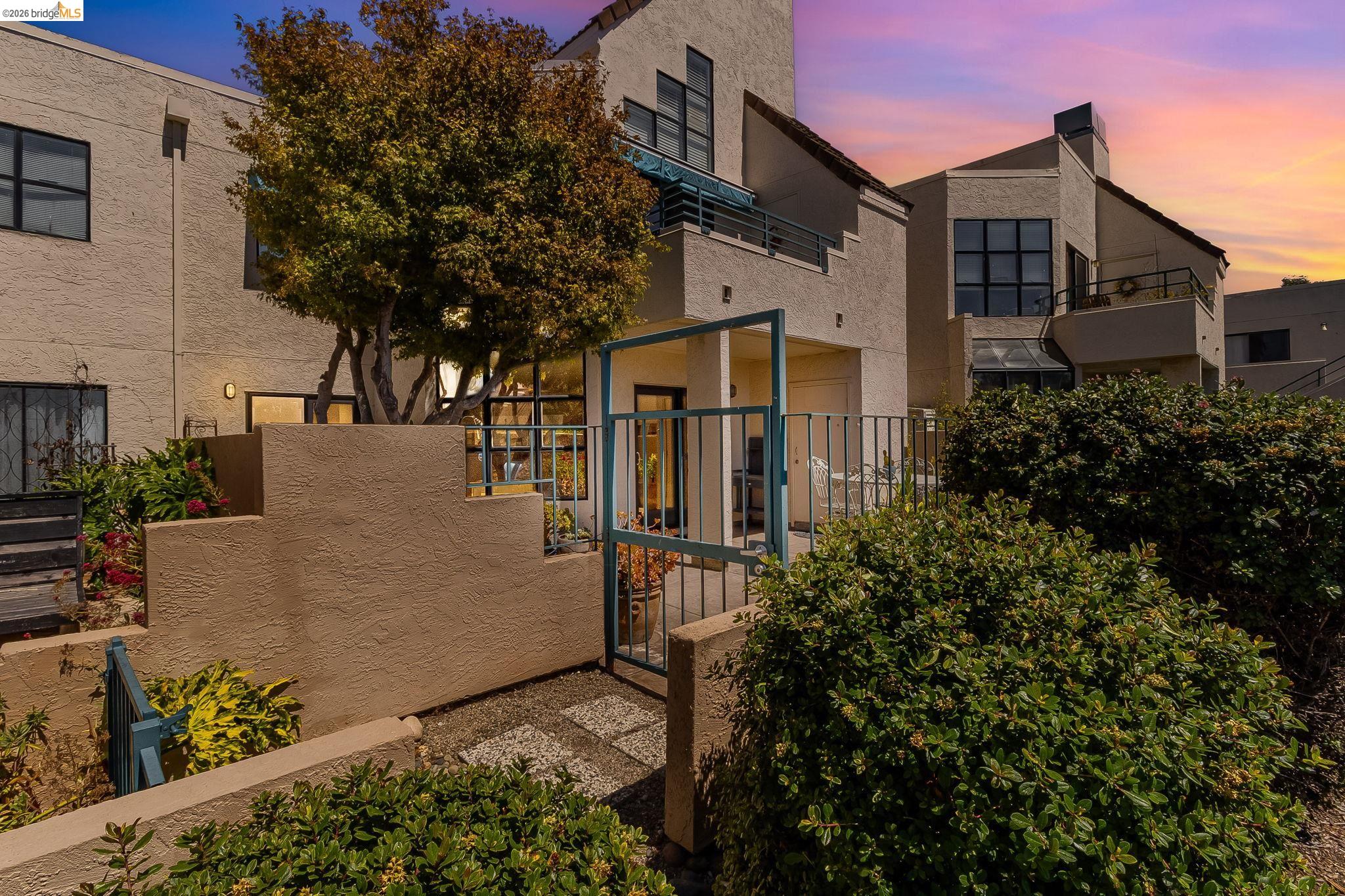Multi-story stucco home with teal courtyard gates and balconies at dusk.