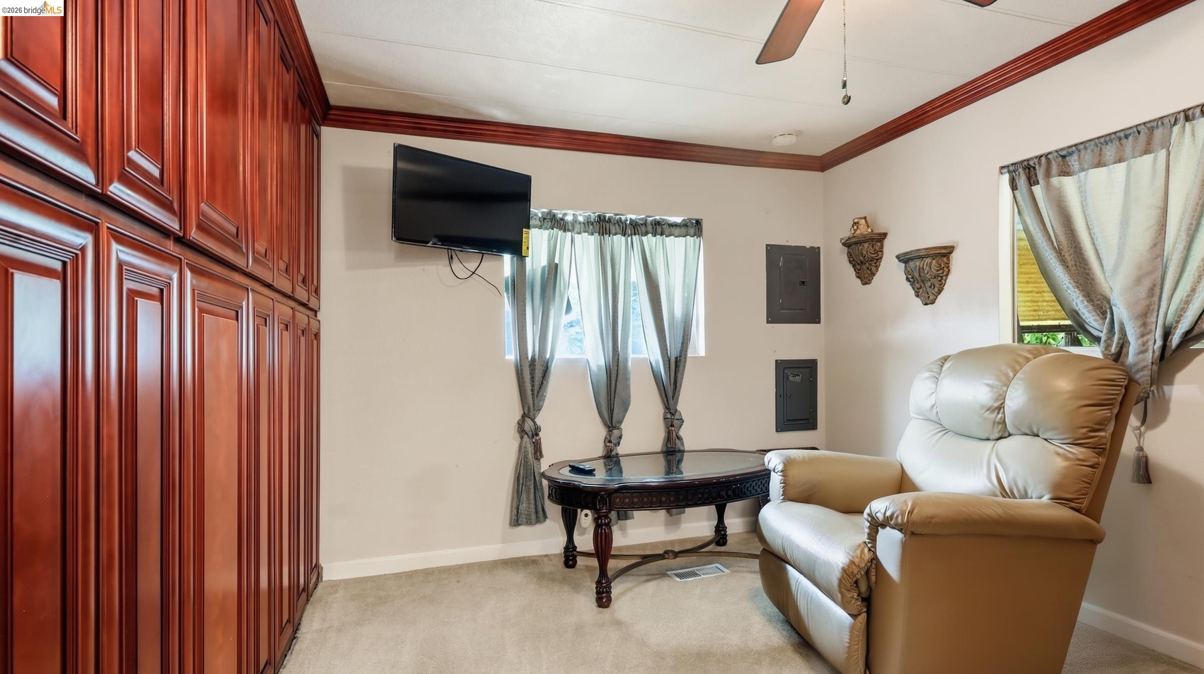 Room with reddish built-in cabinets, a wall-mounted TV, and a cream leather recliner.