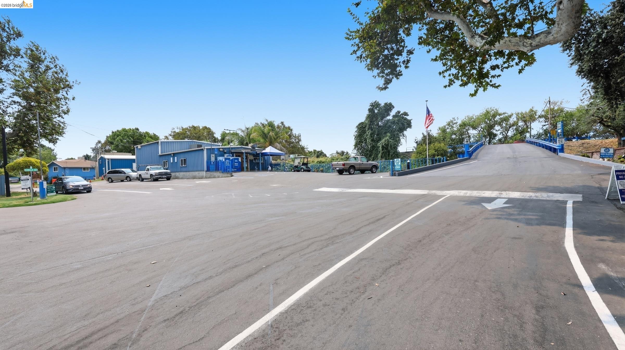 Marina parking area with a blue building and raised, blue-railed ramp.