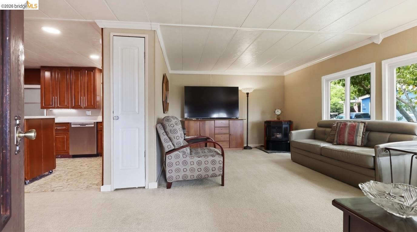Living room with a large sofa and patterned armchair, opening onto a dark-wood kitchen.