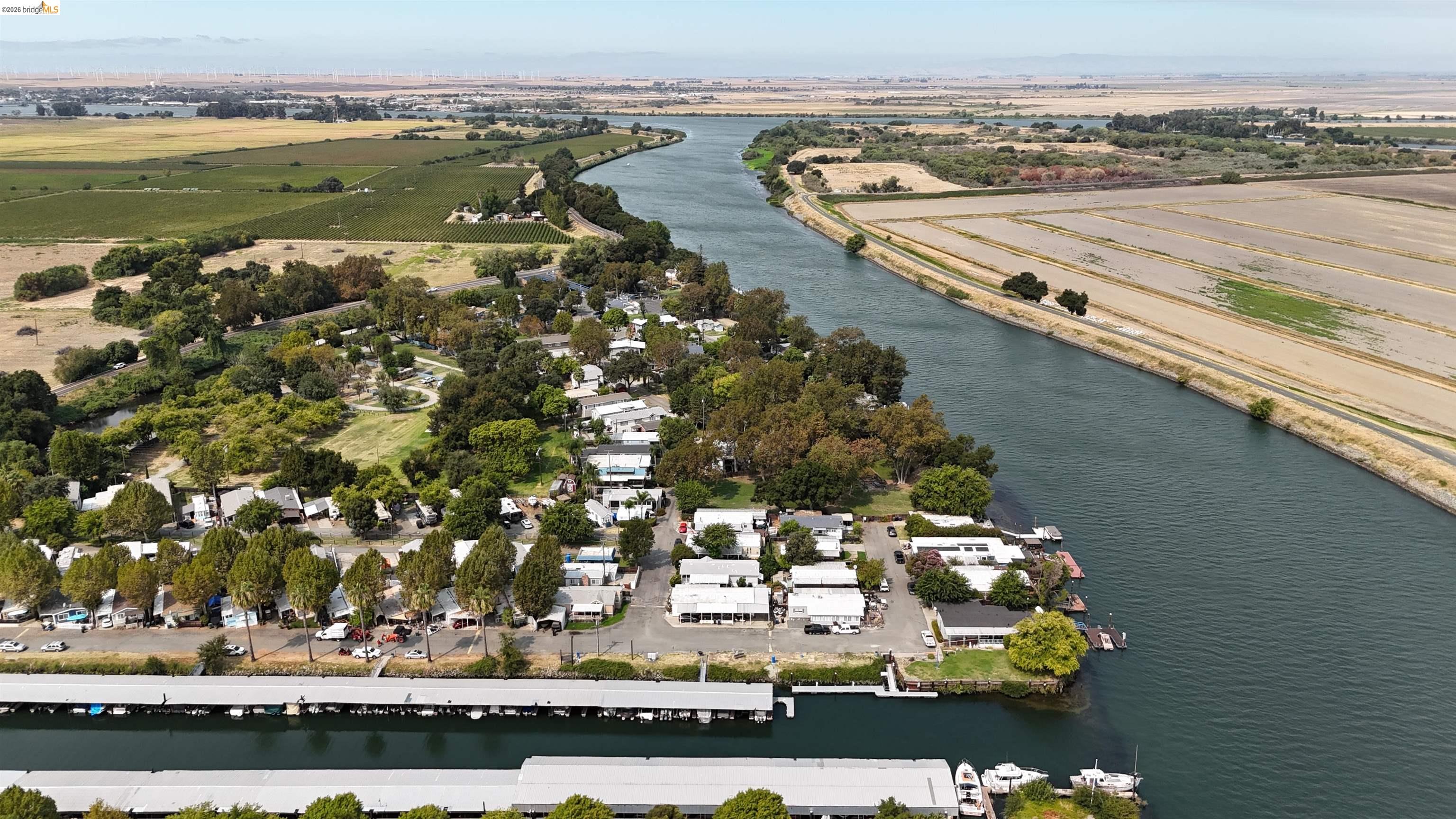 Riverside community beside a broad river, with covered boat slips and farmland visible from above.