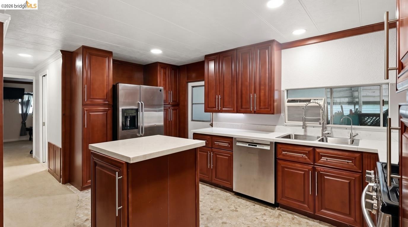 Kitchen with dark wood cabinets, a white-topped island, stainless appliances, and a double-basin sink.