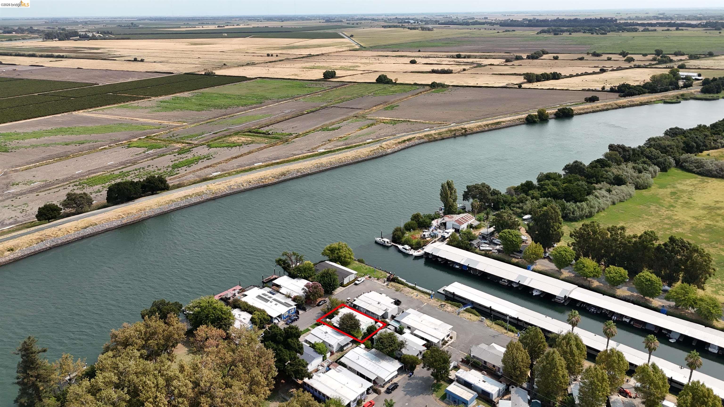 Aerial view of the red-outlined property beside a waterway and covered boat docks.