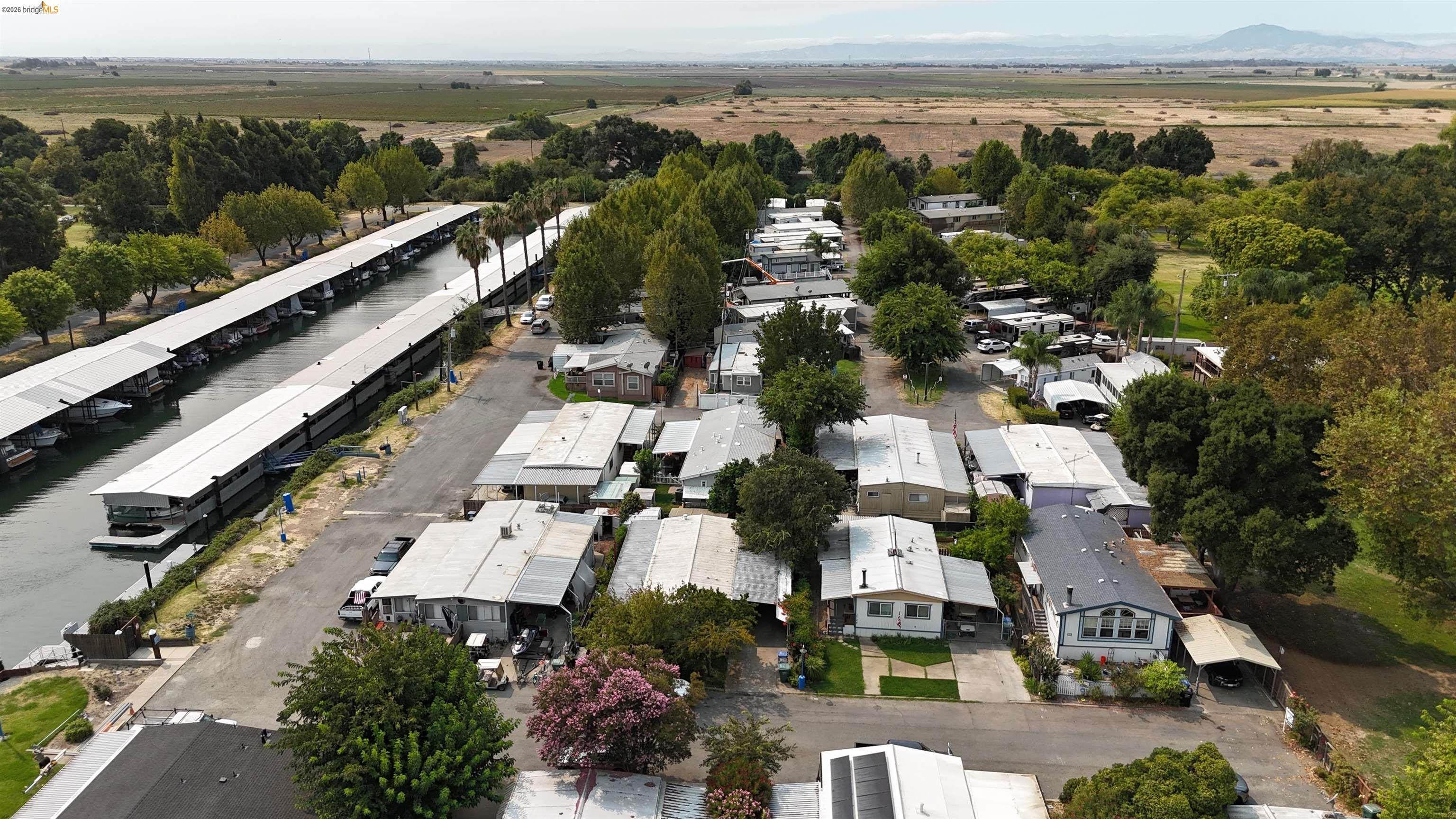 Aerial view of homes beside a canal with long covered boat slips.