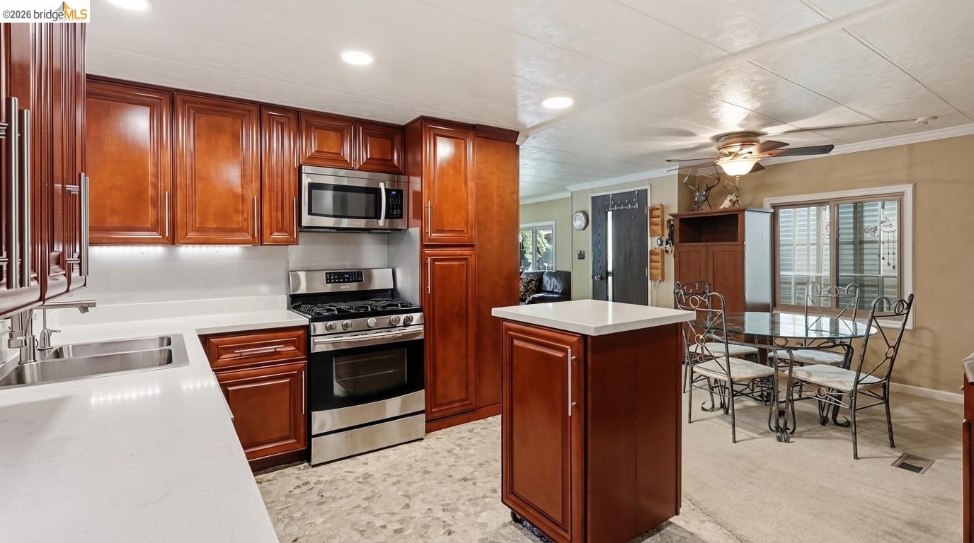 Kitchen with reddish-brown wood cabinetry, a central island, and an adjoining dining area.
