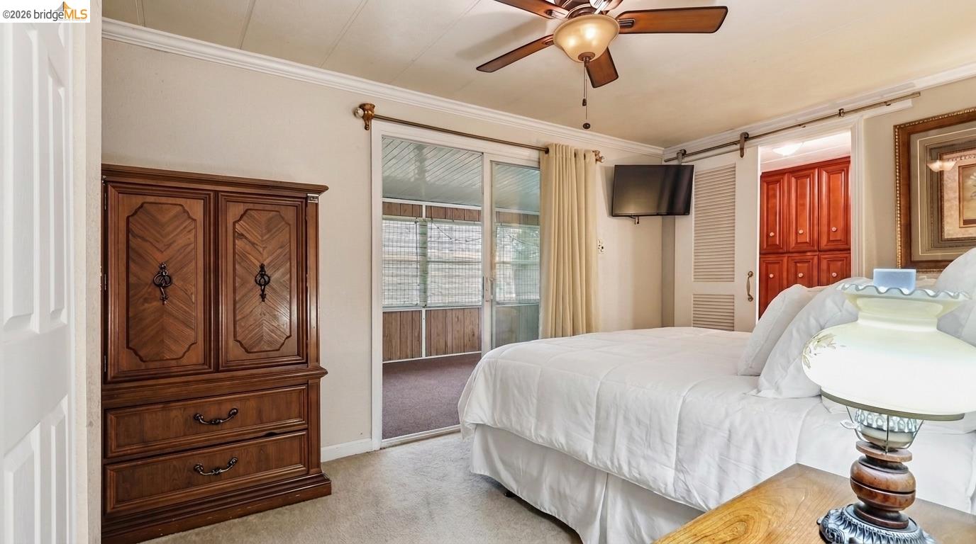 Bedroom with a white bed, dark wood armoire, and sliding glass doors to an enclosed porch.