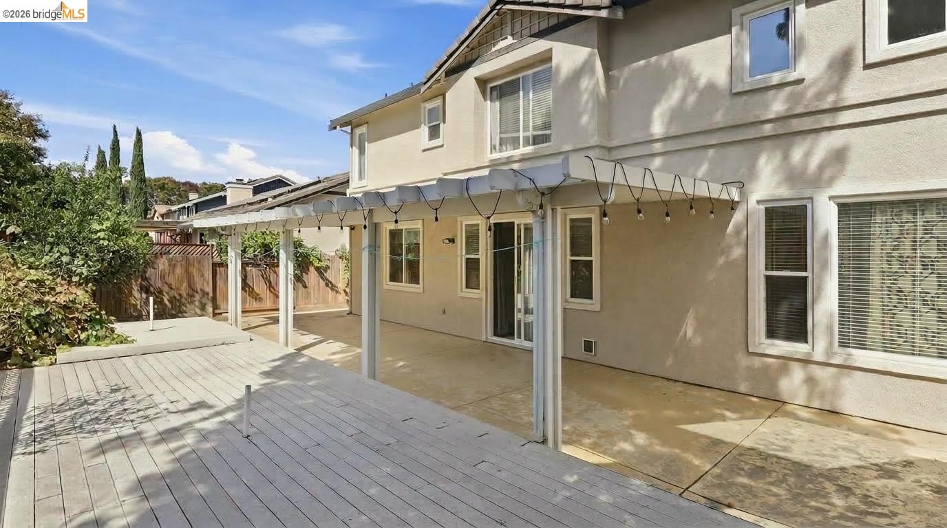 Rear of a two-story stucco home with a covered patio and broad deck.