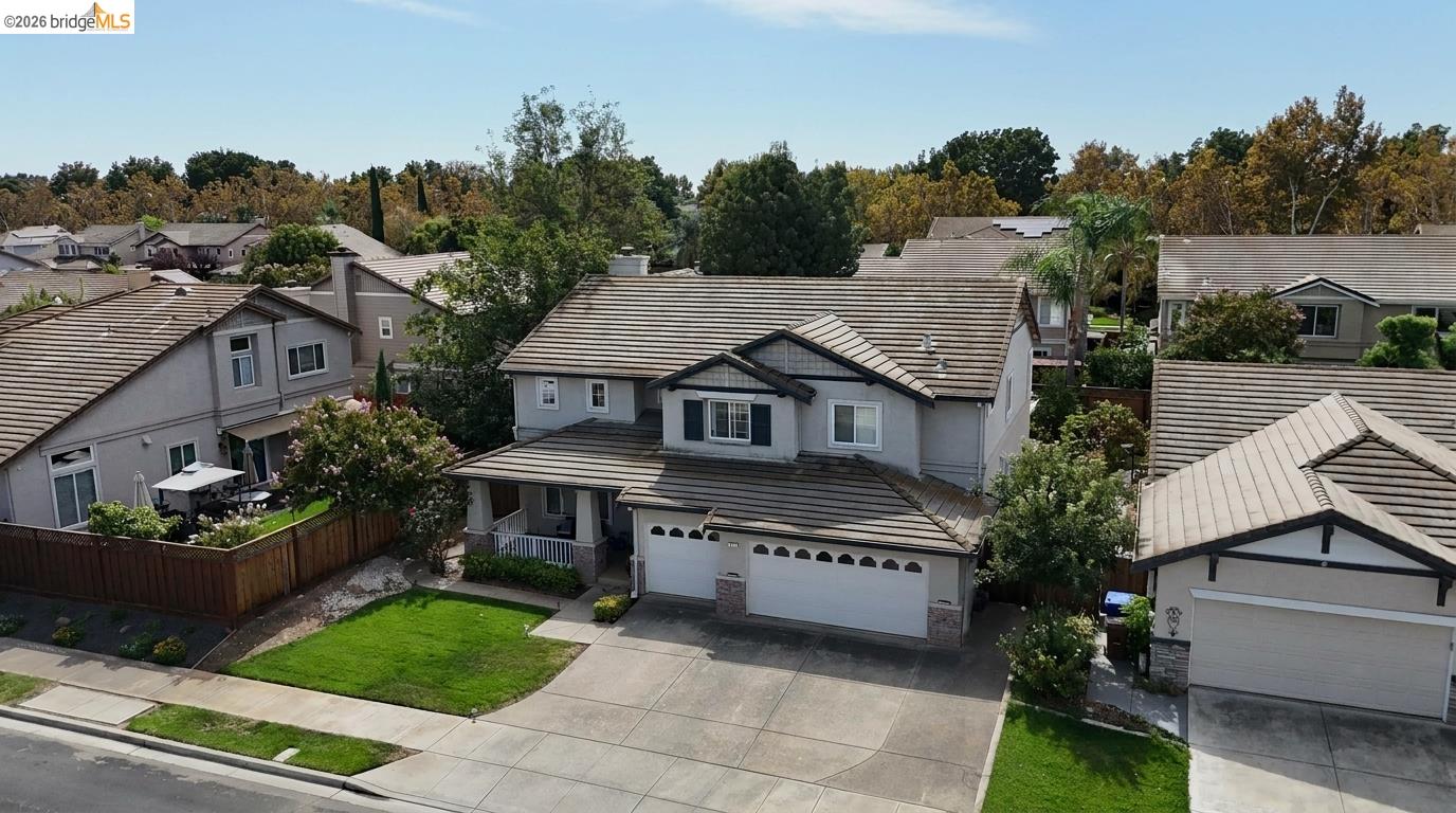 Two-story gray home with tiled roof, double garage, and front lawn, viewed from above.