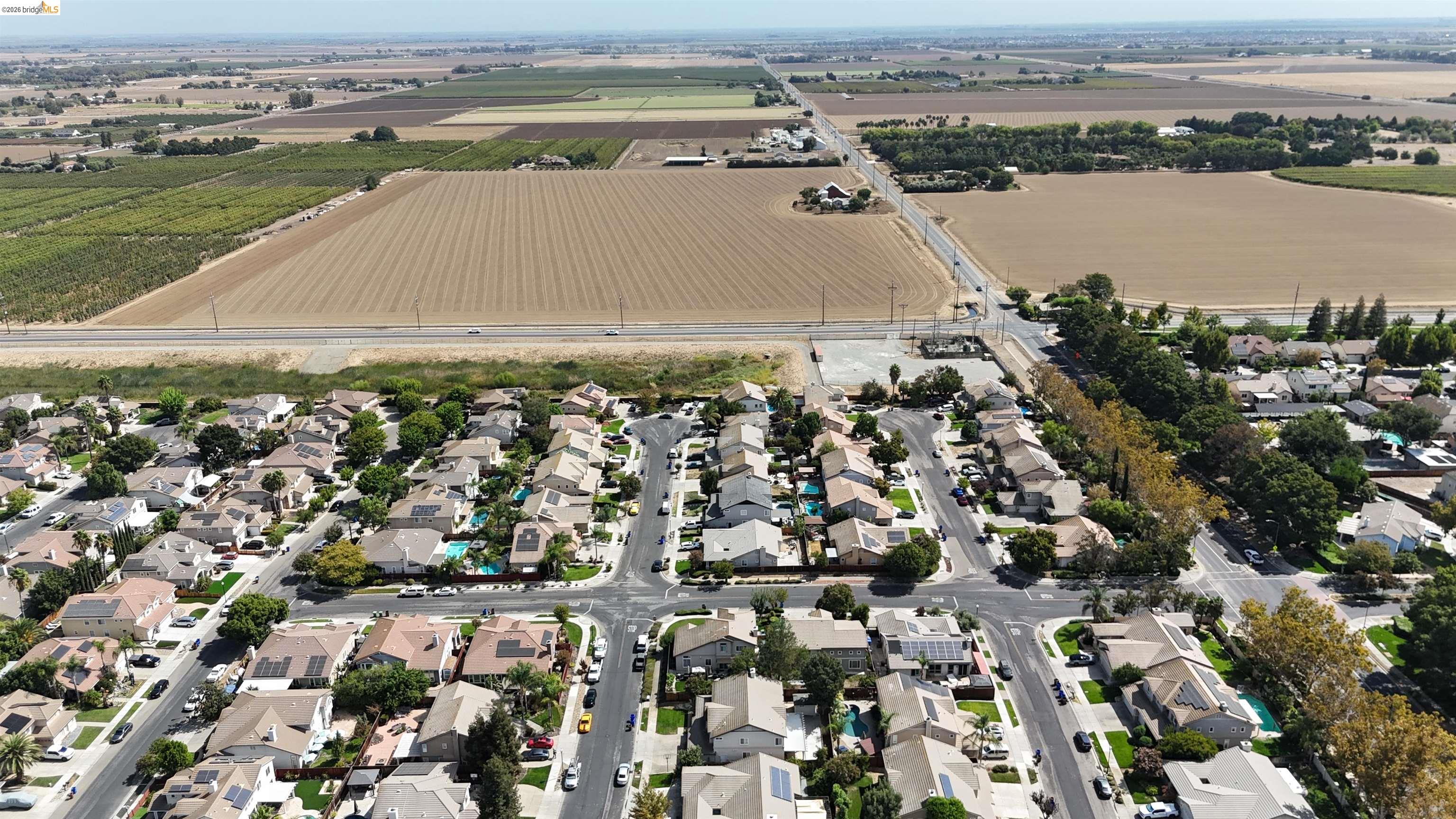 Aerial view of a residential neighborhood beside broad cultivated fields.