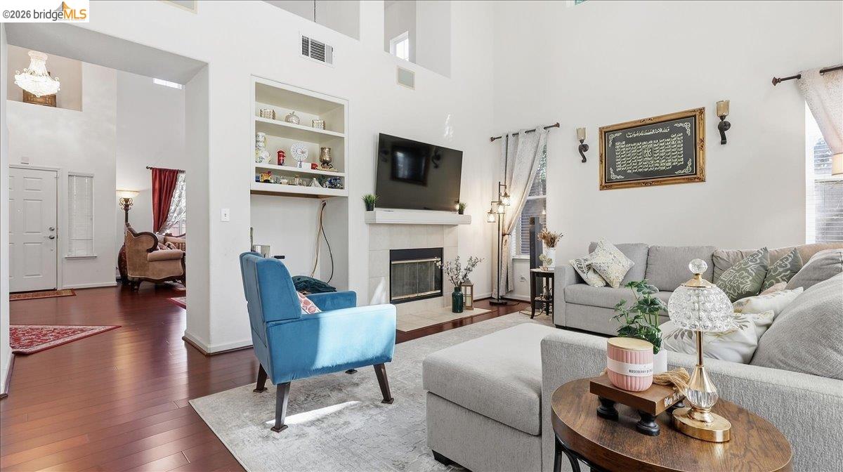 Living room with a gray sectional, blue accent chair, fireplace, and high ceiling.