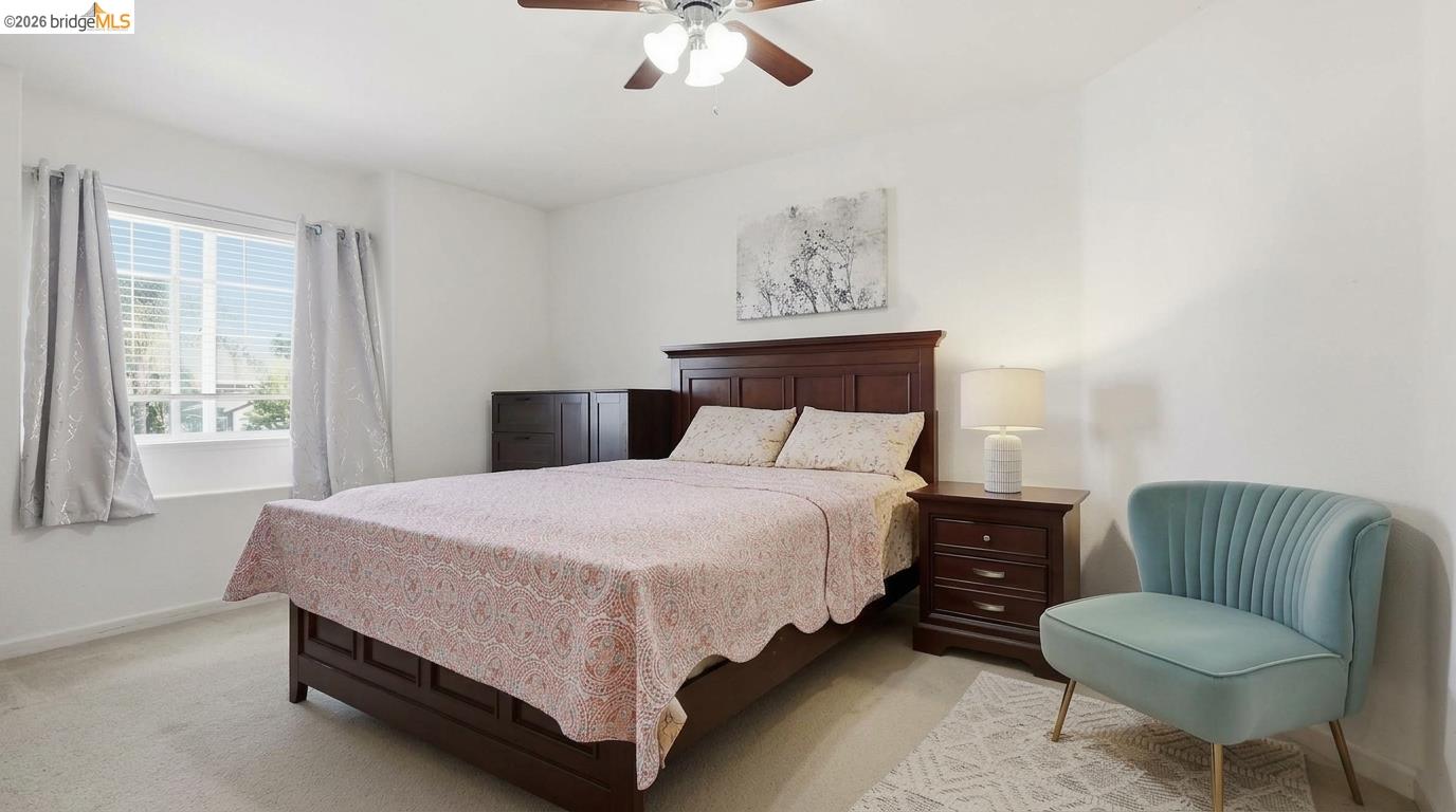 Furnished bedroom with a dark wood bed, gray-curtained window, and teal accent chair.