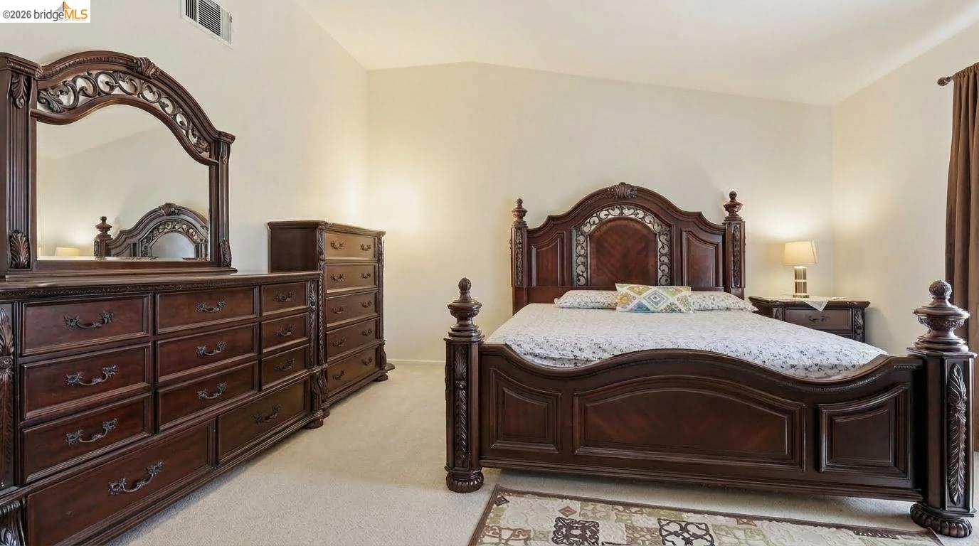 Bedroom with an ornate dark wood bed and matching dresser and mirror.