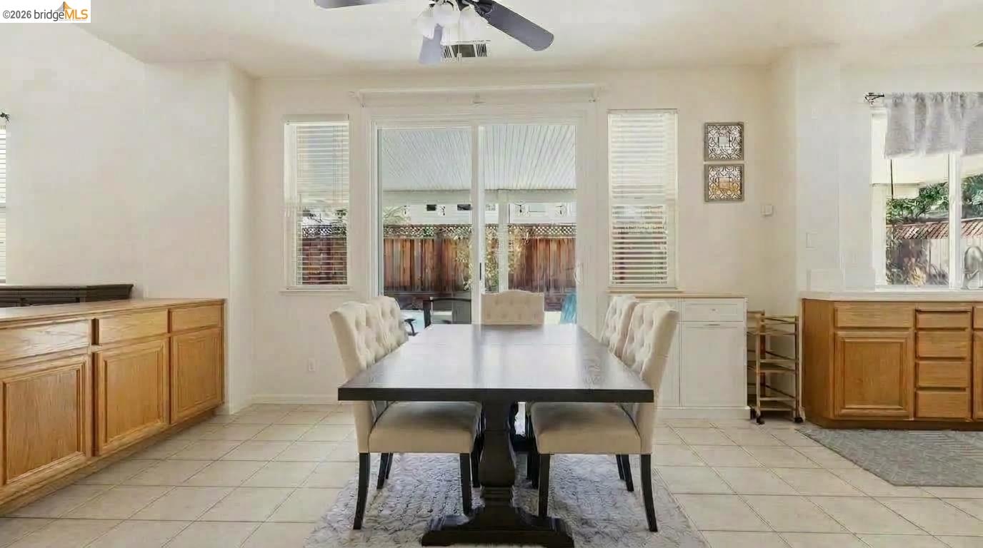 Dining area with a dark table, upholstered chairs, wood cabinetry, and sliding doors to the backyard.