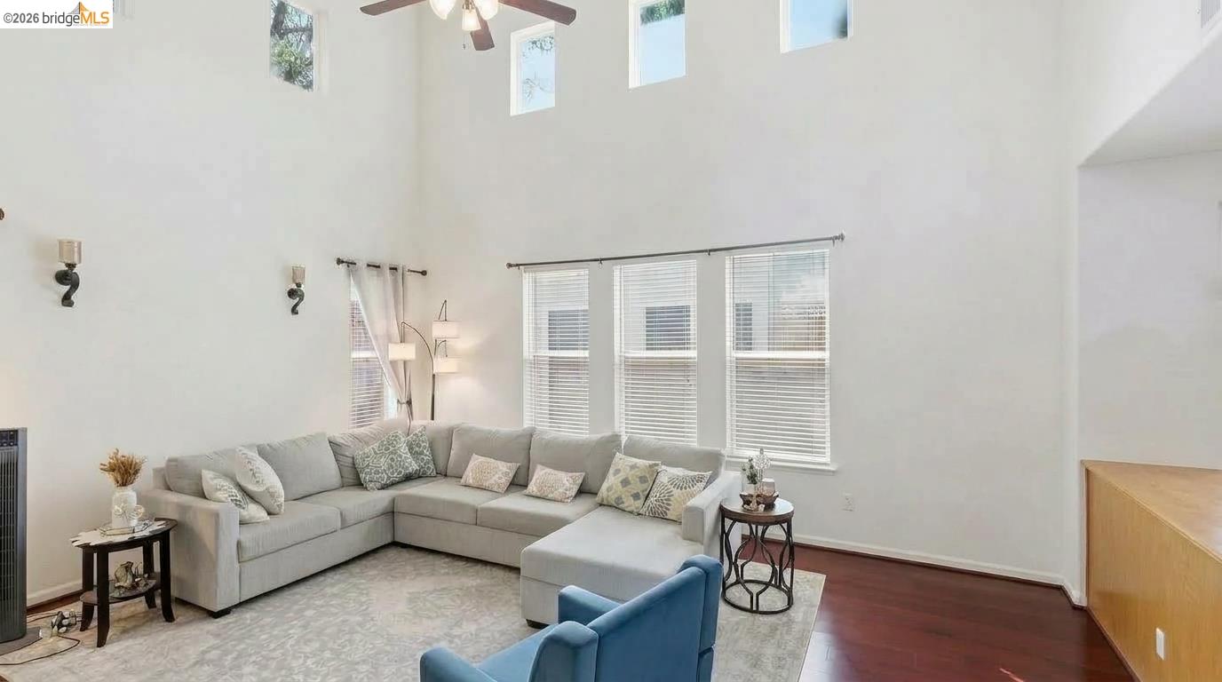 Living room with a gray sectional beneath a vaulted ceiling and high windows.