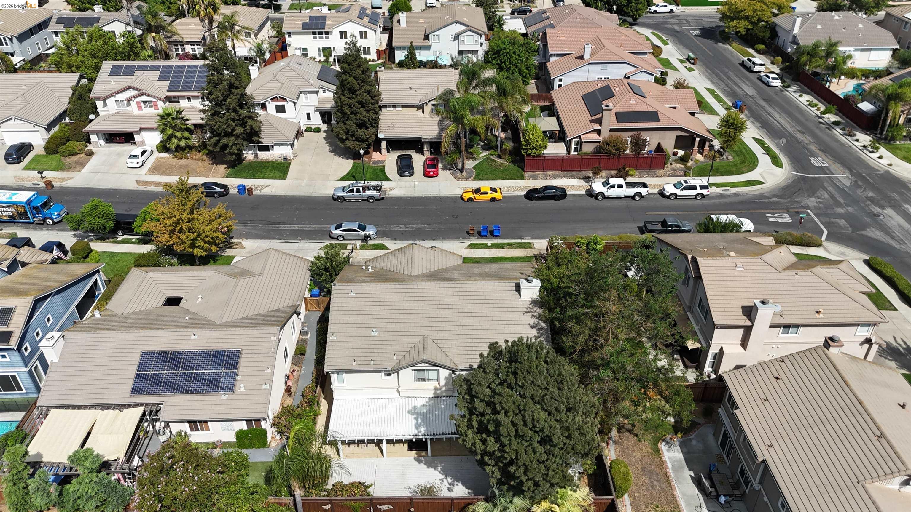 Aerial view of a suburban residential block with tree-lined streets and homes with solar panels.