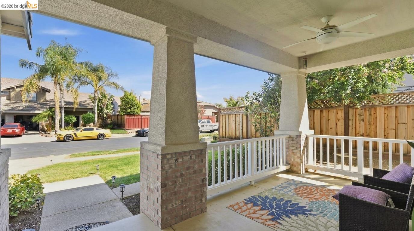 Covered porch with white railing and outdoor seating overlooking the front yard and street.