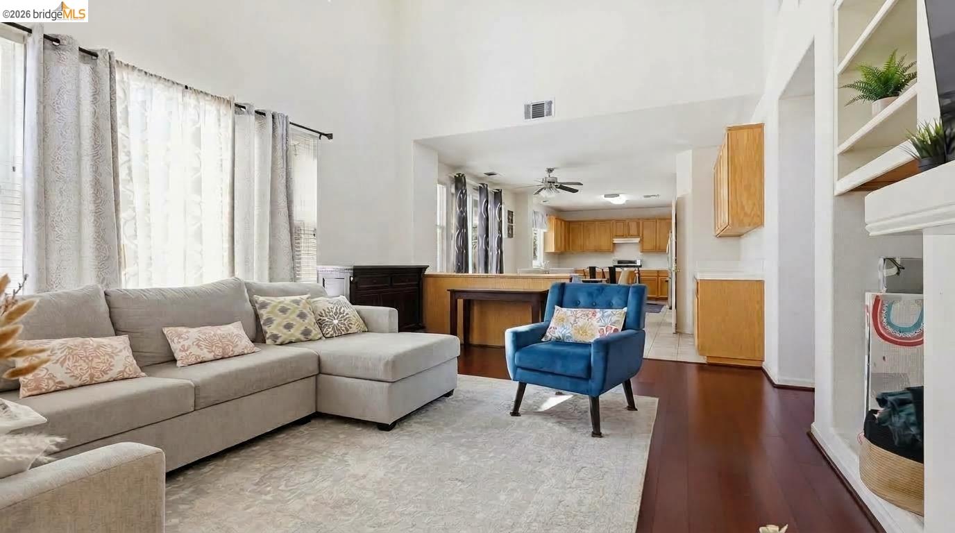 Living room with a beige sectional and blue chair opening into a kitchen.