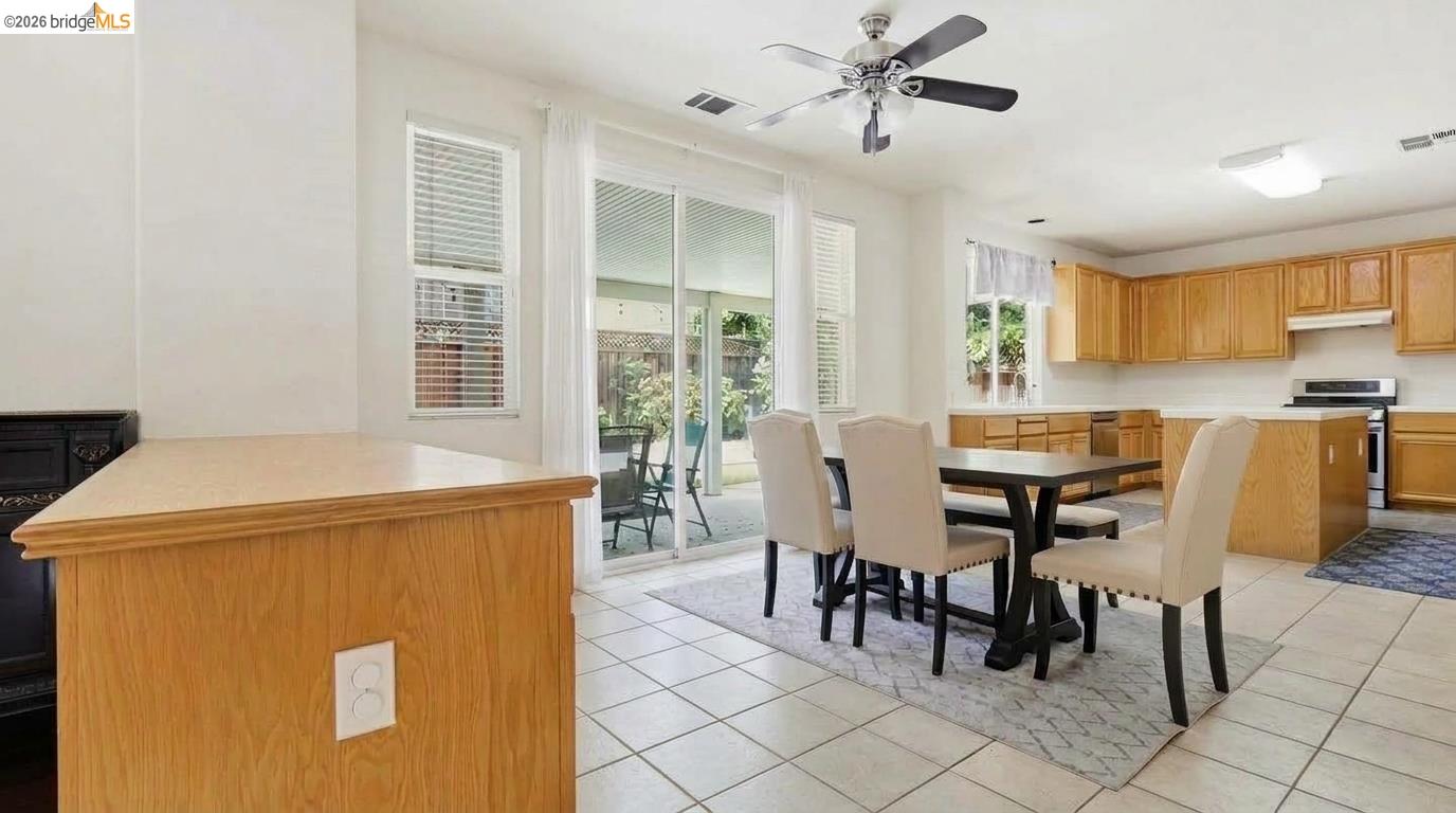 Kitchen and dining area with wood cabinetry, tiled floors, and sliding glass doors to a patio.