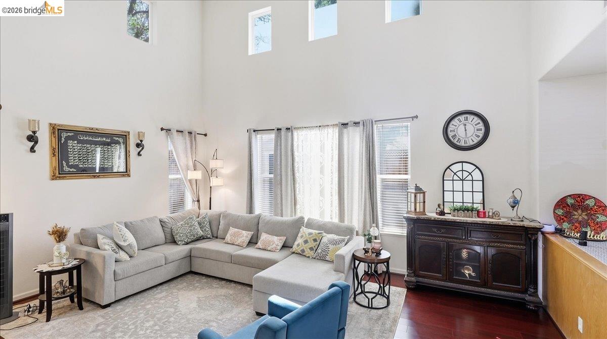 Living room with a gray sectional beneath a vaulted ceiling and tall windows.