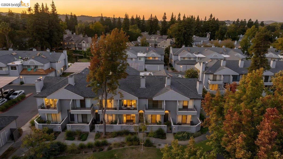 Aerial view of attached homes at sunset, with autumn trees and wooded hills beyond.