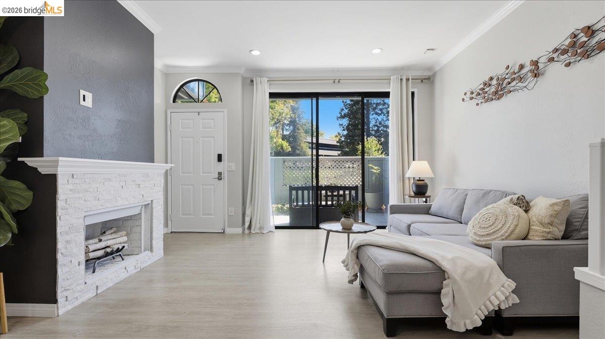 Living room with a white stone fireplace, gray sectional, and sliding glass doors to a patio.
