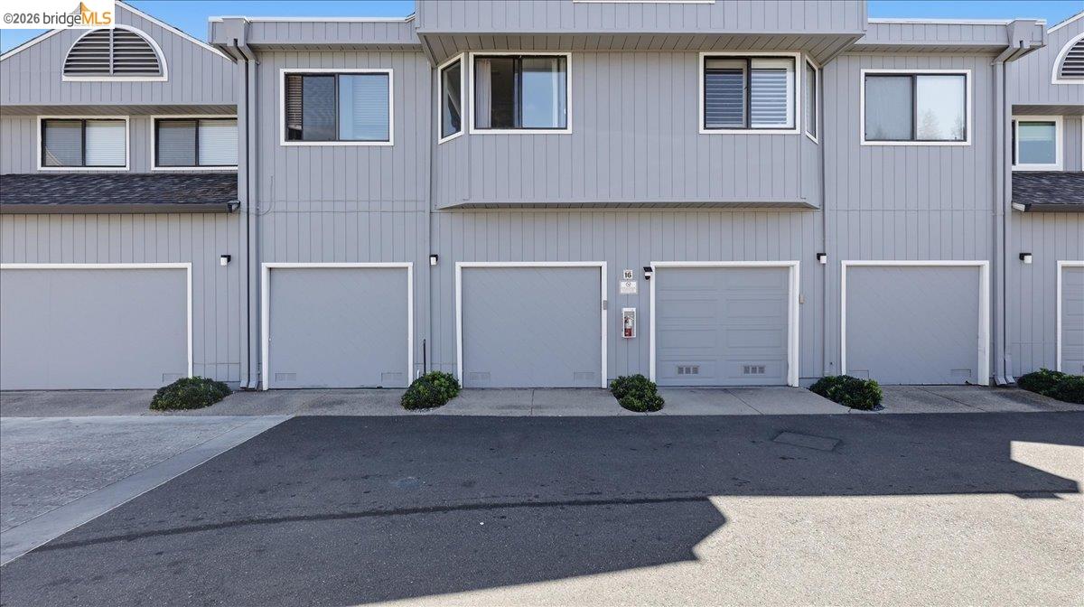 Gray-sided residential building with multiple garage doors and upper-floor windows.