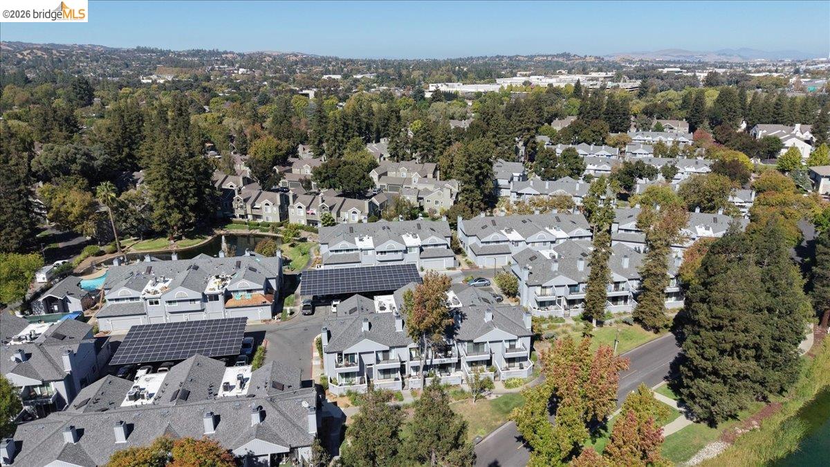 Aerial view of attached homes with solar panels among tree-lined streets.