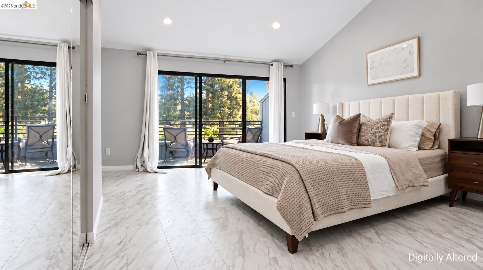 Staged bedroom with an upholstered bed, mirrored closet doors, and sliding glass doors to a balcony.