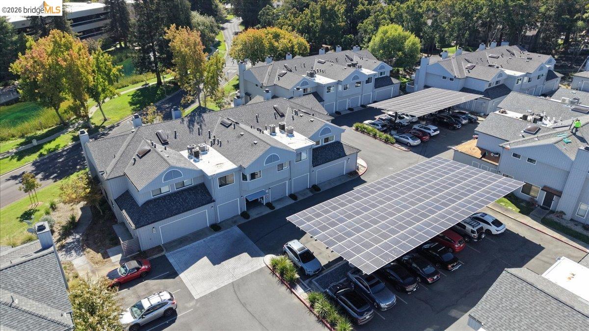 Aerial view of attached homes and parking beneath solar-panel canopies.
