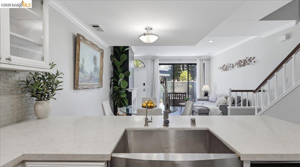 Open-plan kitchen with a wide white counter and sink overlooking the dining and living areas.