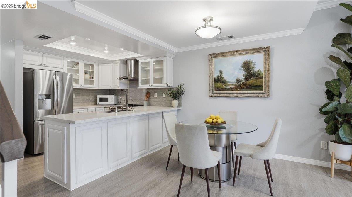 Bright white kitchen with stainless appliances, a large island, and an adjoining round dining table.