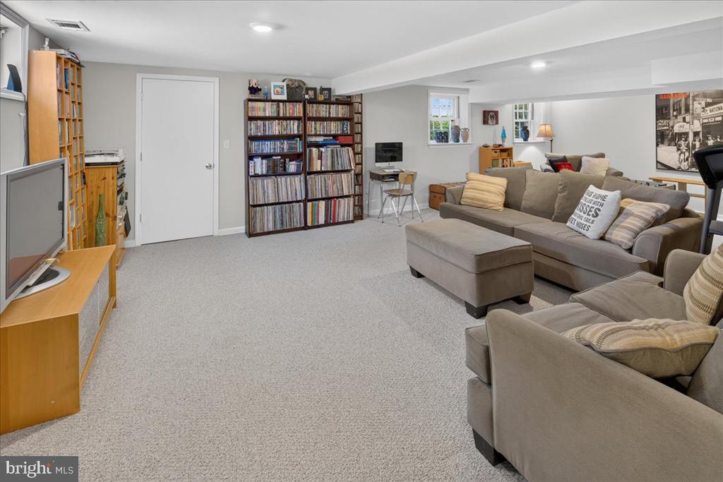 Finished basement family room with carpet, sectional sofas, bookshelves, and a television.