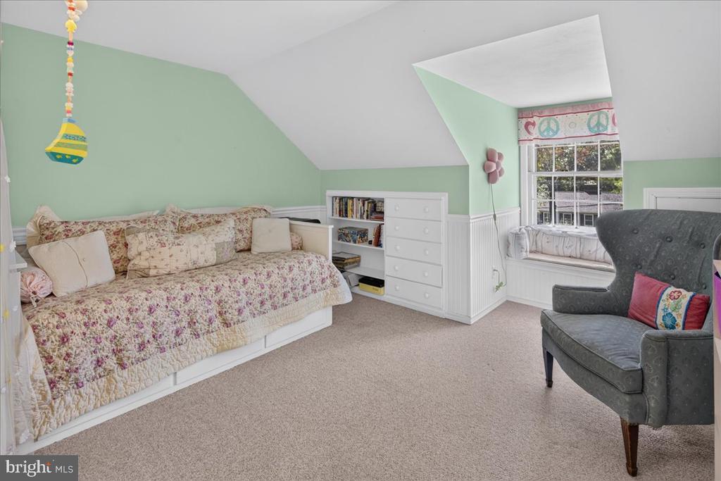 Bedroom with a floral daybed, built-in drawers, mint-green walls, and a window-side armchair.
