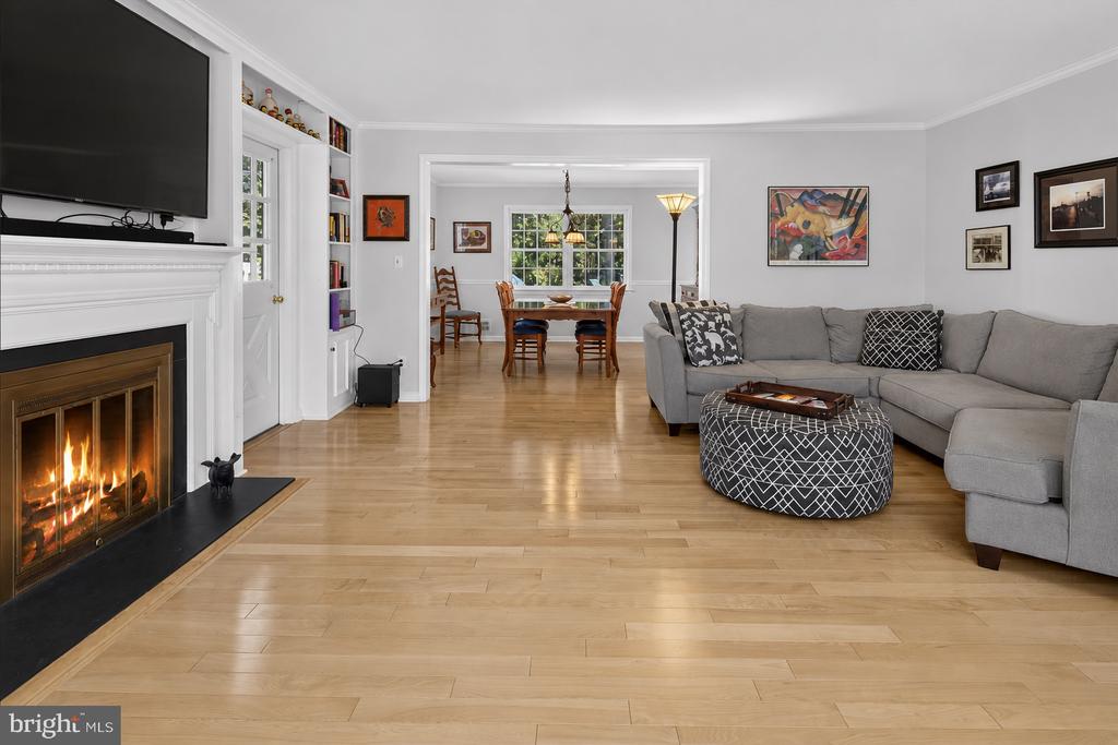 Living room with gray sectional, hardwood floors, fireplace, and adjoining dining area.