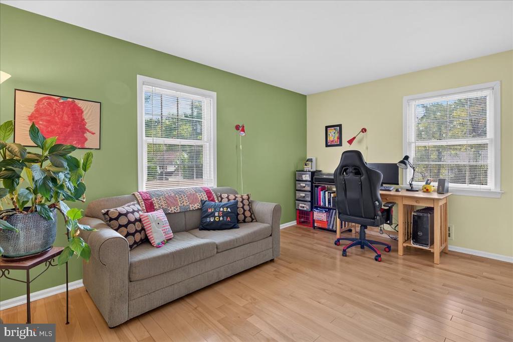 Home office and sitting room with a gray sofa, wooden desk, and green walls.