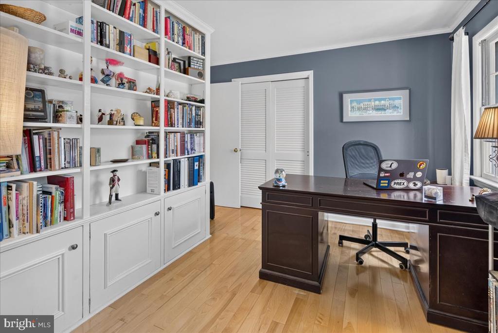 Home office with built-in bookshelves, a dark wood desk, and hardwood floors.