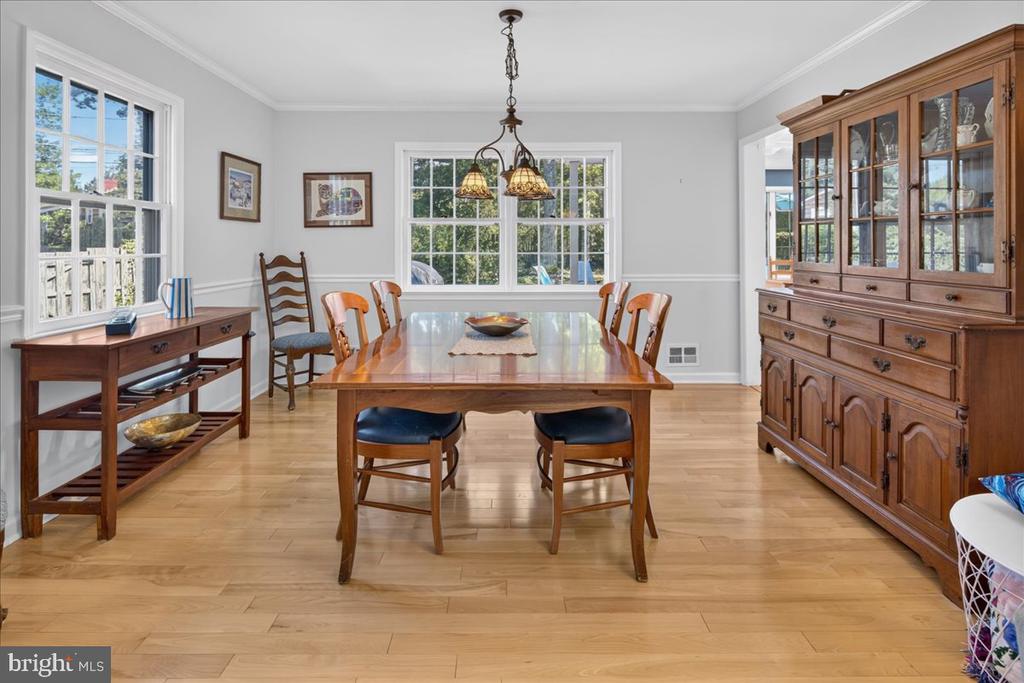 Dining room with a wooden table, glass-front china cabinet, and large windows.