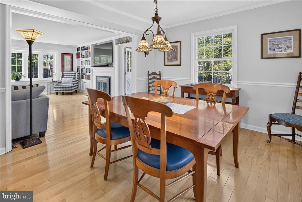 Dining room with a wooden table, blue-cushioned chairs, and an open view into the living room.