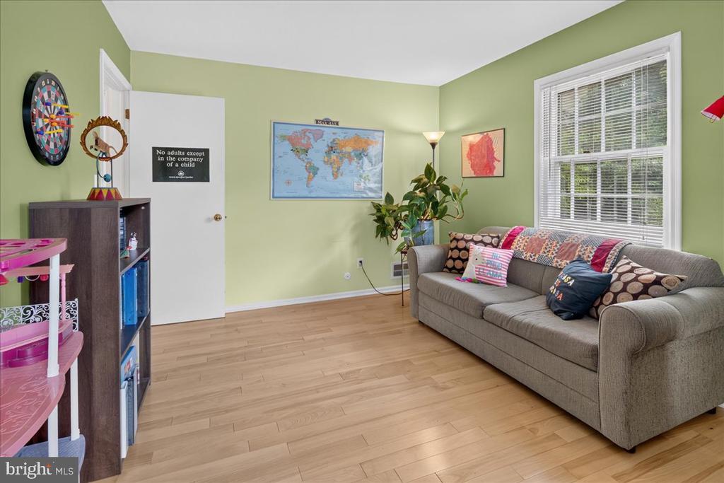 Living room with a gray sofa, pale green walls, a world map, and children's toys.