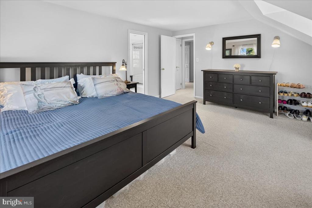 Bedroom with a dark wood bed, blue quilt, matching dresser, and shoe rack.