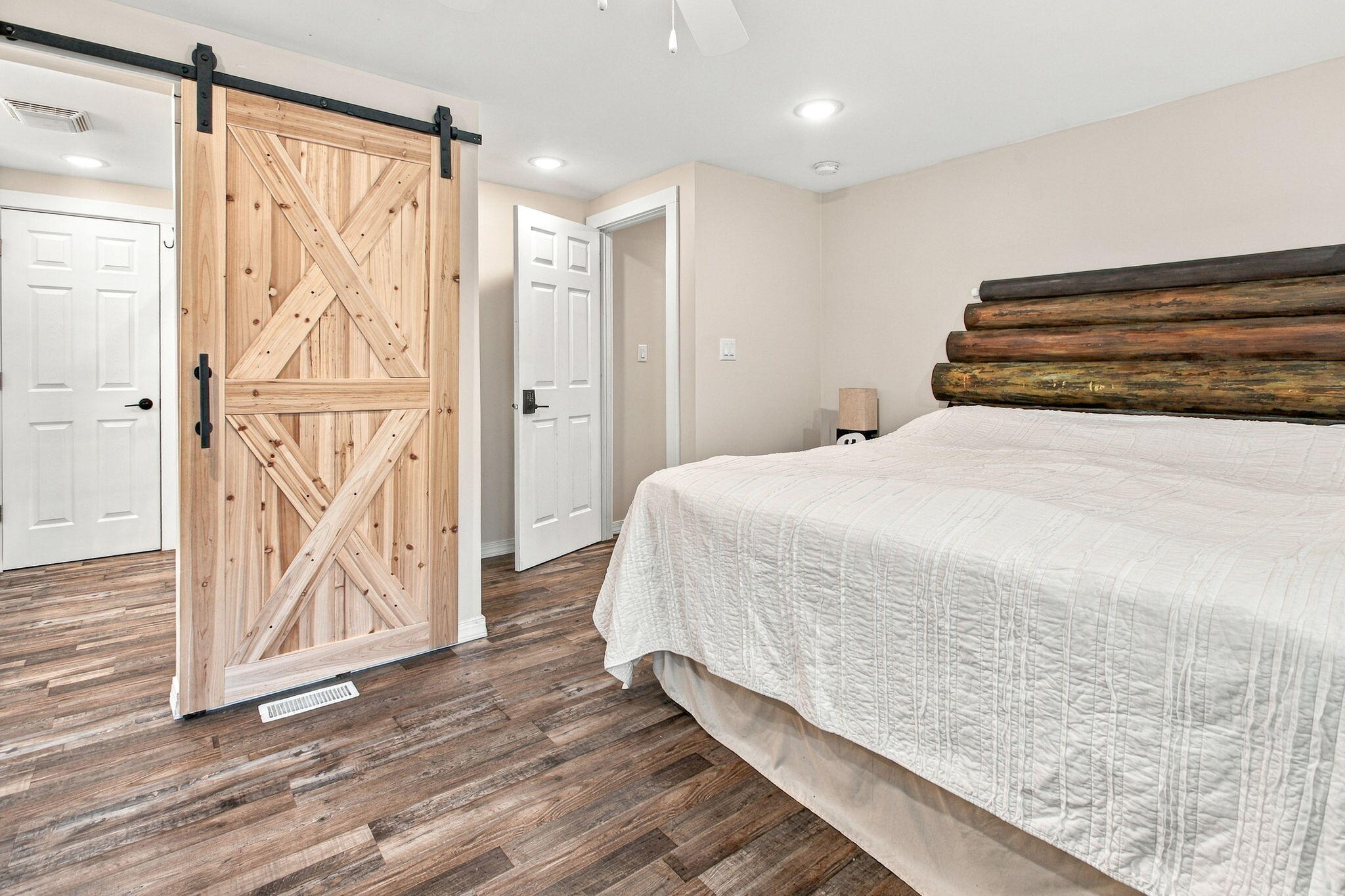 Bedroom with a rustic log headboard and sliding wooden barn door.