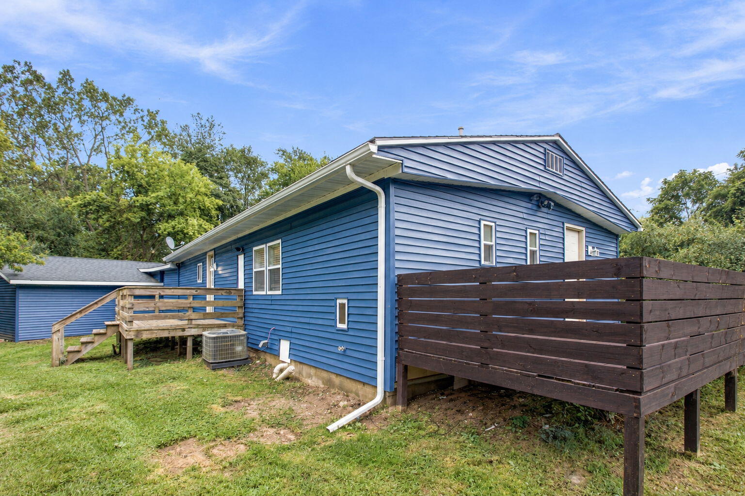 Blue-sided house with a raised wooden deck and dark privacy fence.