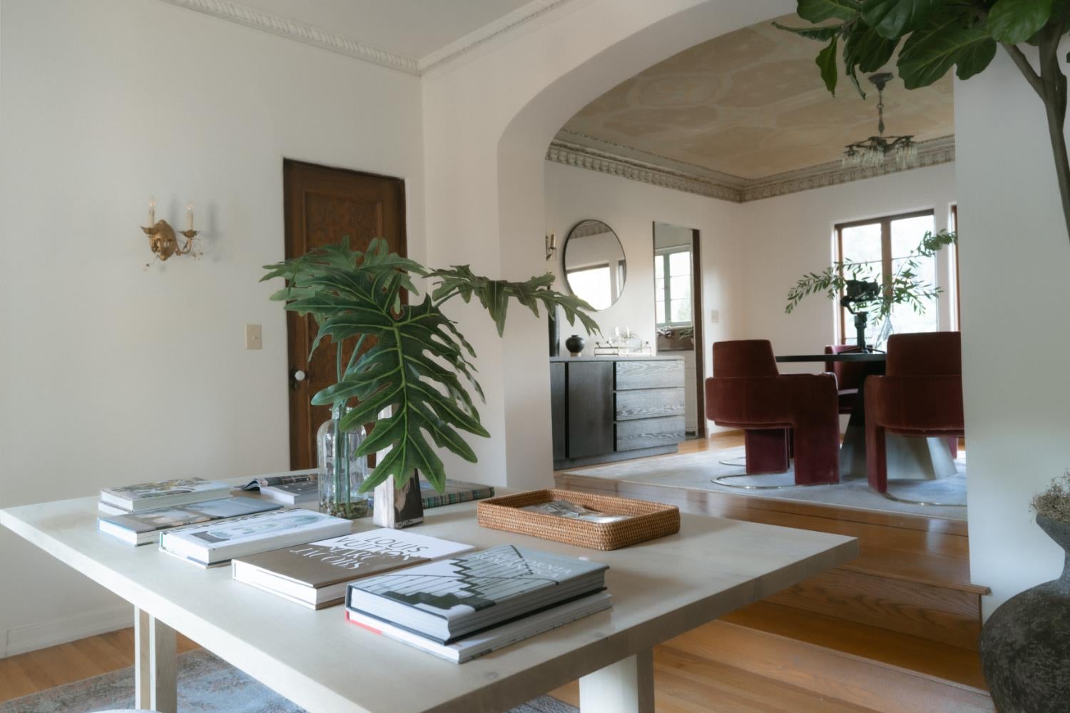 Staged living room with a white coffee table, broad archway, and burgundy dining chairs.