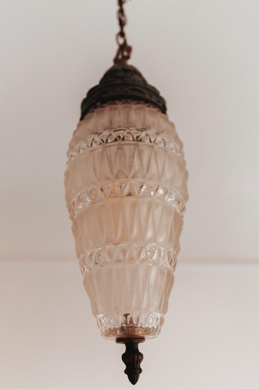 Vintage pendant light with a faceted glass shade and dark metal chain.