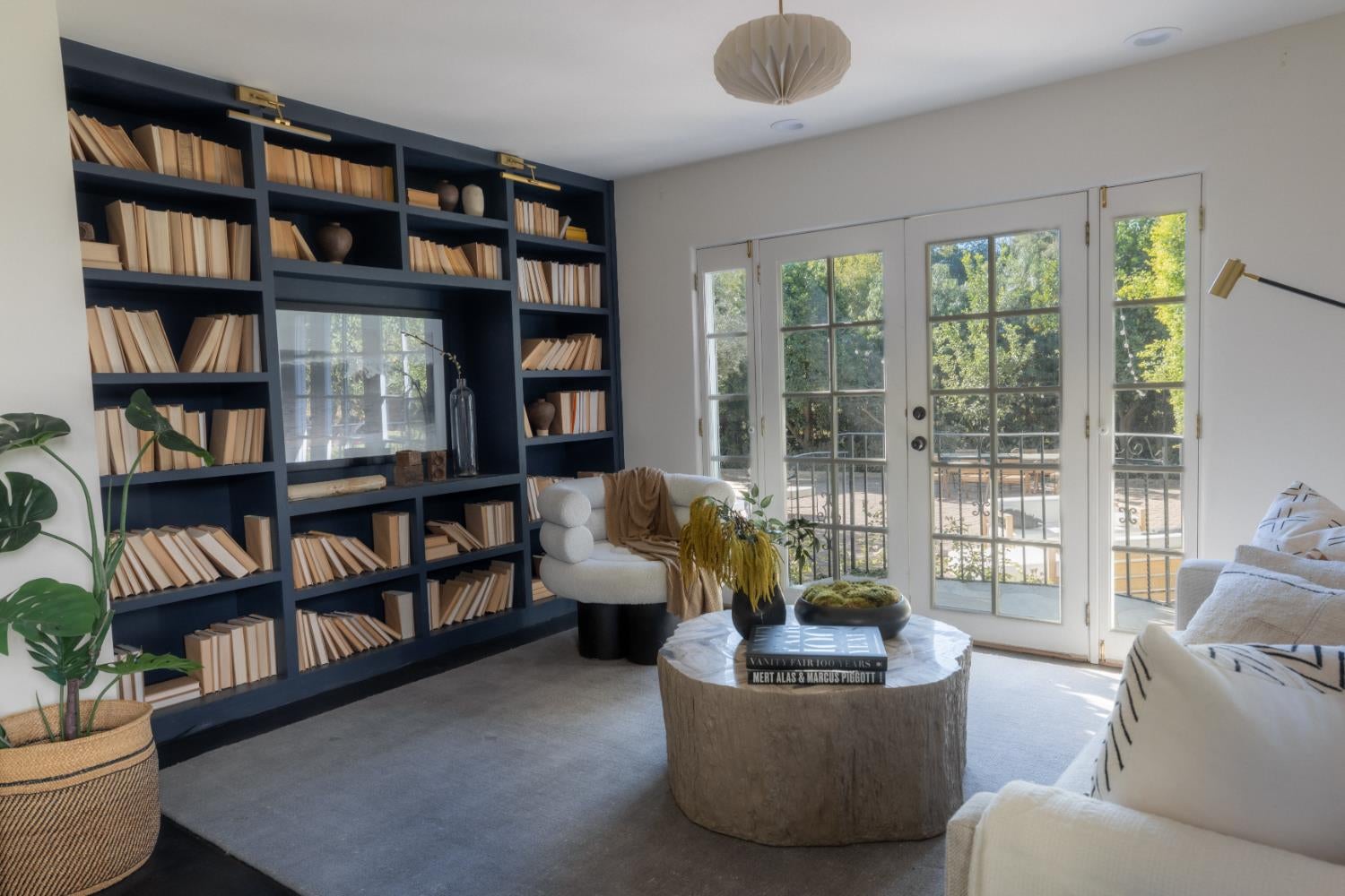 Living room with navy built-in bookshelves and glass French doors opening to a patio.