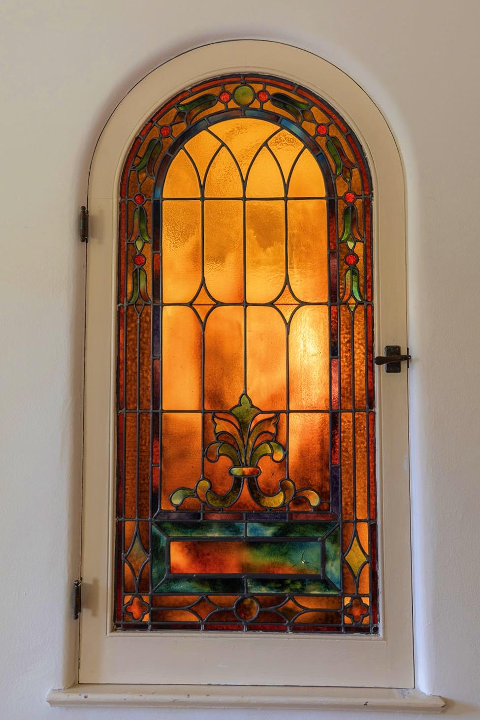 Arched stained-glass door with an ornate amber, orange, green, and red panel.