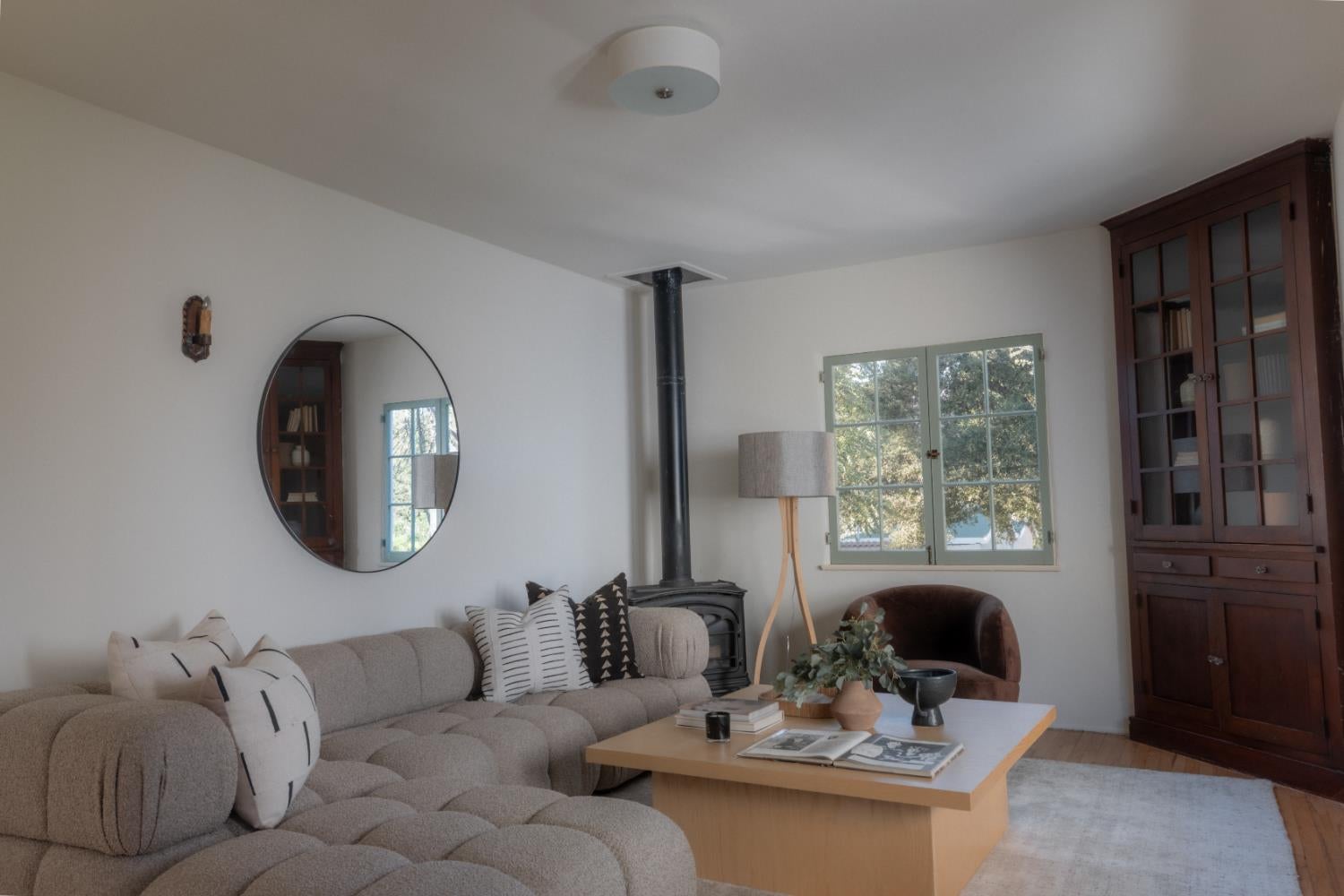 Living room with a tufted sectional, wood stove, and dark wood glass-front cabinet.