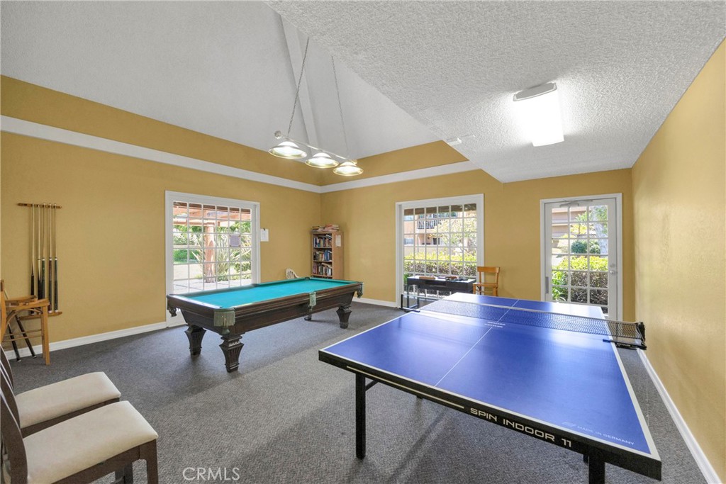 Recreation room with a blue ping-pong table, teal pool table, and windows.